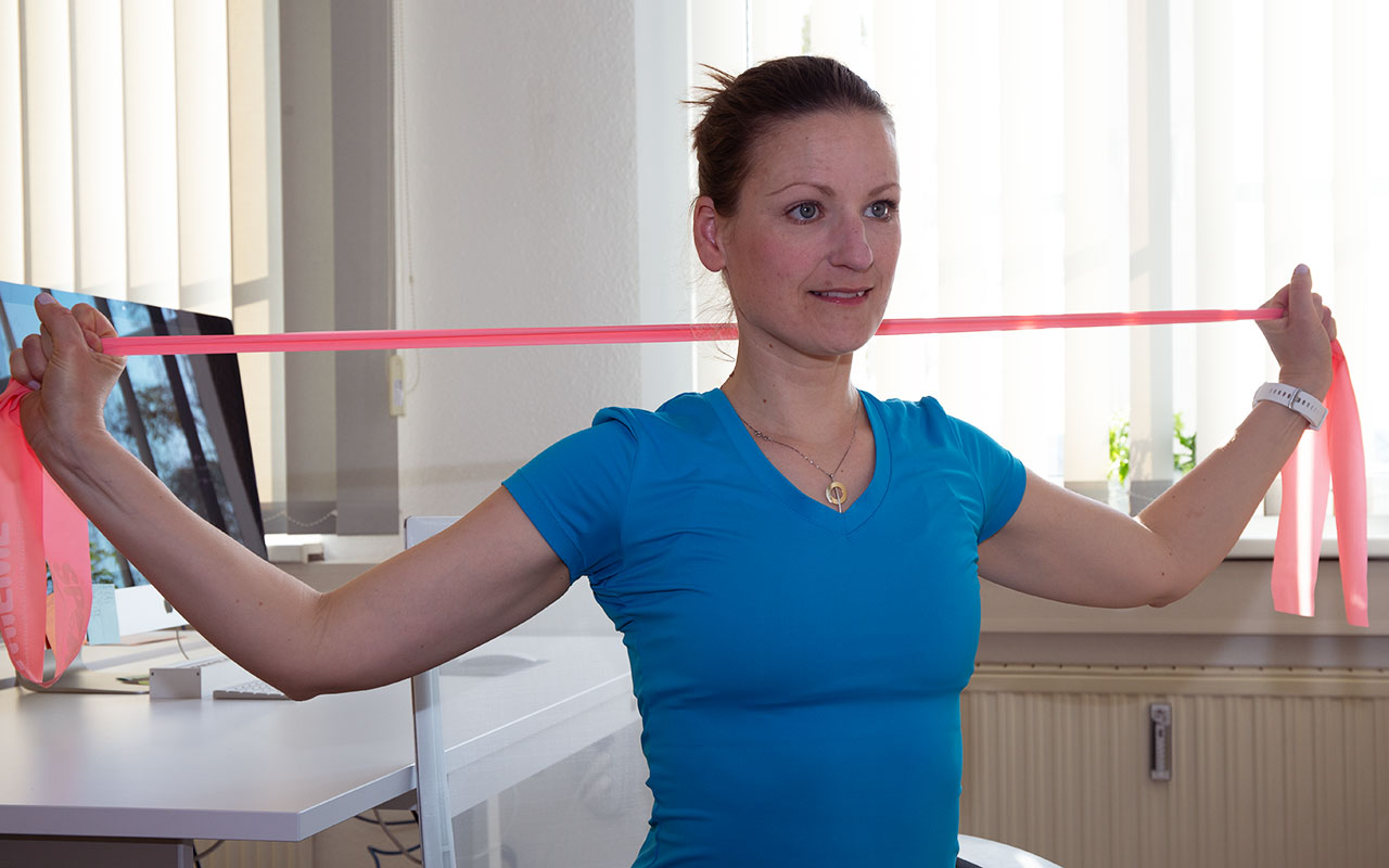 Trainerin Anke mit Thera-Band im Büro